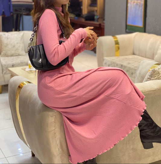 Woman in a pink dress sitting on a couch in an indoor setting